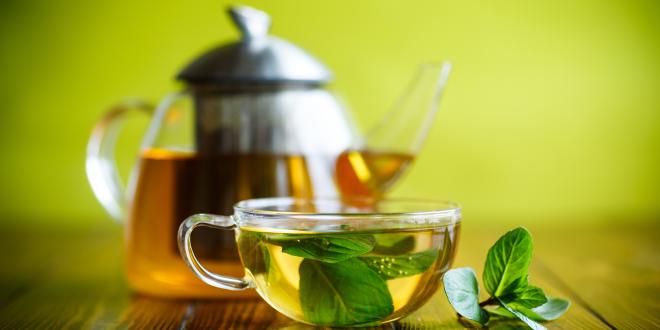 a kettle and cup of loose-leaf green tea