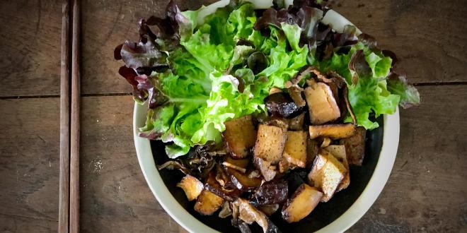 a bowl of stir-fried mushrooms and tofu, garnished